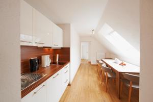 a kitchen with white cabinets and a table with chairs at Hotel Nordwind in Langeoog