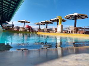 - une piscine avec des tables, des chaises et des parasols dans l'établissement Imo Apart Pipa's Ocean, à Pipa