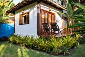 a house with two chairs on the front porch at Barra Suítes in Barra Grande