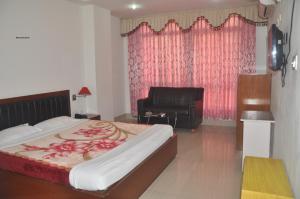 - une chambre avec un grand lit et une chaise dans l'établissement Hotel Dooars Mountain, à Alīpur Duār
