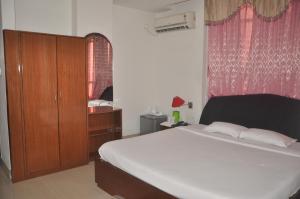 a bedroom with a large bed with a wooden cabinet and a window at Hotel Dooars Mountain in Alīpur Duār