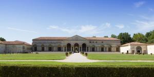 a large building with a pathway in a field at Dimore al Te in Mantova