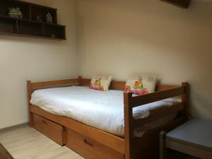 Schlafzimmer mit einem Holzbett mit weißer Bettwäsche und Kissen in der Unterkunft Gîte Toul, 2 pièces, 3 personnes - FR-1-584-60 in Toul