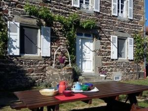 a wooden picnic table in front of a stone building at Gîte Mazeyrat-d'Allier, 4 pièces, 5 personnes - FR-1-582-200 in Mazeyrat-d'Allier