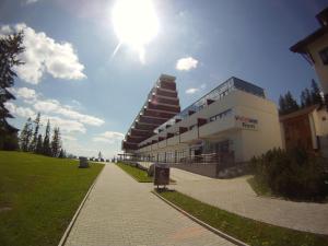 a large building with the sun in the sky at Apartman Panorama 213, Štúdio Comfort in Štrbské Pleso