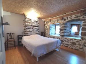 um quarto com uma cama e uma parede de pedra em Gîte Retournac, 3 pièces, 4 personnes - FR-1-582-319 em Retournac