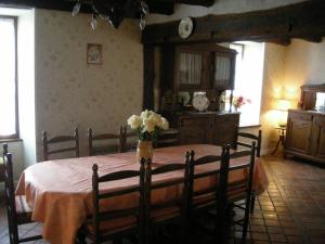 a dining room table with a vase of flowers on it at Maison Authentique en Berry avec Jeux, Jardin, à 30 min du Zoo de Beauval - FR-1-591-119 in Gehée