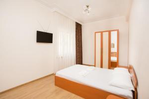a white bedroom with a bed and a television at Hotel Teplo in Sochi