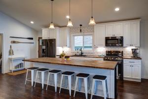 een keuken met witte kasten en een groot eiland met barkrukken bij Blue Fish Cottage in Waterford