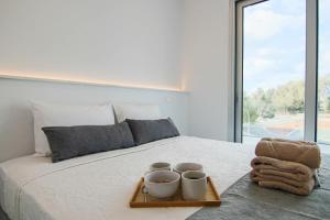 ein Bett mit einem Tablett mit drei Tassen darauf in der Unterkunft Phaedrus Living - Seaside Executive Flat Harbour 205 in Paphos
