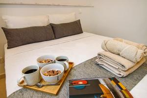 ein Bett mit einem Tablett mit Essen und Tassen Kaffee in der Unterkunft Phaedrus Living - Seaside Executive Flat Harbour 205 in Paphos