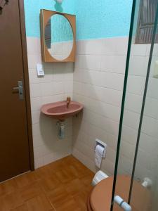 baño con lavabo rosa y espejo en Casa de temporada no centro de arraial do cabo, en Arraial do Cabo