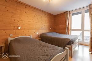 Duas camas num quarto com paredes de madeira em Résidence Le Pied des Pistes C6 em Lanslevillard