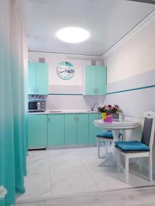 una cocina con armarios azules y una mesa blanca en Tiffany apartment in the center, en Dnipro
