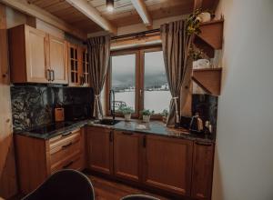 a kitchen with wooden cabinets and a large window at Osada Snozka - domki w górach z balią i kominkiem in Kluszkowce