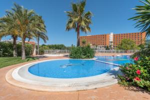 a swimming pool with palm trees and a building at Apartment Es Mirador 2 in Calas de Mallorca