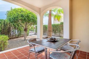 eine Veranda mit einem Tisch, Stühlen und einer Palme in der Unterkunft Apartment Es Mirador 2 in Cales de Mallorca