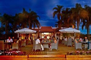 a group of people sitting at tables on a deck at Resort&House,4 Quartos, 8 pessoas, Beach tenis, Bike, Golfe, Pesca, Ar, Wifi fibra, TV a cabo e Lareira in Santa Bárbara do Rio Pardo
