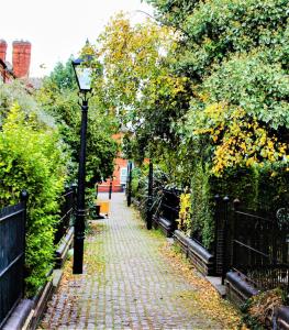a cobblestone path with a street light and trees at The Avenue House in Leicester