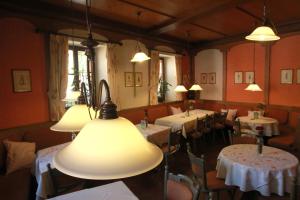 a dining room with tables and chairs and lights at Weinhotel Rose in Volkach