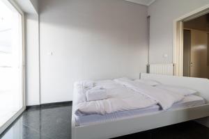 ein weißes Bett in einem weißen Zimmer mit einem Spiegel in der Unterkunft An adorable Apartment in Athens in Athen