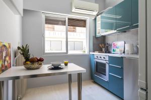 a kitchen with blue cabinets and a table with a bowl of fruit at Superb apartment in the heart of Athens in Athens
