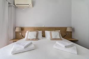 a white bed with three pillows on it at Superb apartment in the heart of Athens in Athens