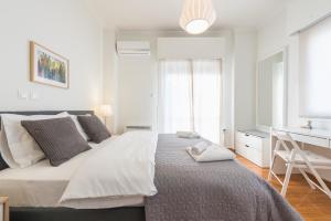 ein weißes Schlafzimmer mit einem großen Bett und einem Schreibtisch in der Unterkunft Cozy and fresh apt close to Metro in Athen