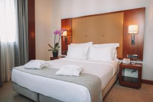ein Hotelzimmer mit einem großen Bett mit Handtüchern darauf in der Unterkunft Hotel Dom Carlos Liberty in Lissabon