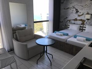 a room with two beds and a chair and a table at Apartment In Porta Batumi Tower in Batumi