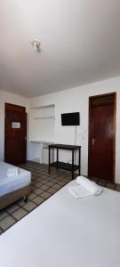 a room with two beds and a tv on the wall at Pousada Temporada Atlântica in Fortaleza