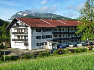 a building with a red roof with a parking lot at Ferienwohnung Allegra in Reit im Winkl