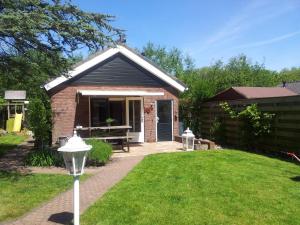 una pequeña casa de ladrillo con un banco en un patio en Zomerhuis De Zeedistel, en Egmond aan den Hoef