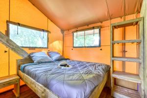 - un lit dans une petite maison avec 2 fenêtres dans l'établissement Camping maeva Escapades Millau Plage, à Millau