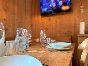 una mesa de madera con platos y gafas y TV en EXCLUSIVES Chalet an der SKIPISTE +Dampfbad +NETFLIX, en Hohentauern