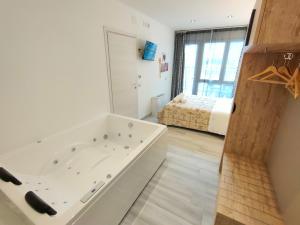 a bathroom with a bath tub and a bedroom at Residence Cristine in Riva del Garda