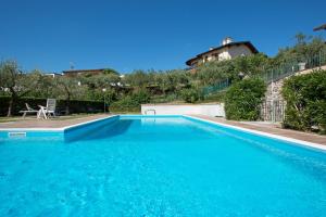 a large blue swimming pool with a house in the background at Le Ortensie 1 Apartment by Wonderful Italy in Soiano del Lago