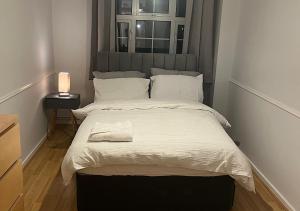 Lovely 2 bedroom apartment with parking space في لندن: غرفة نوم بسرير كبير مع شراشف بيضاء ونافذة