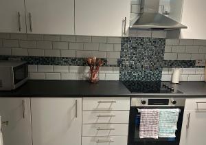 uma cozinha com armários brancos e um forno com placa de fogão em Lovely 2 bedroom apartment with parking space em Londres