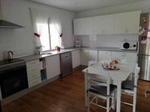 a kitchen with white cabinets and a white table and chairs at Casa de pueblo in Babilafuente
