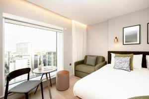 um quarto com uma cama, uma cadeira e uma janela em Wilde Aparthotels London Paddington em Londres