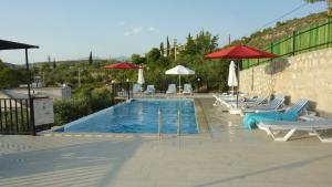 a swimming pool with lounge chairs and umbrellas at Hotel Sema in Patara