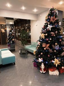 a large christmas tree in a lobby with presents at Park Hotel Fili in Moscow