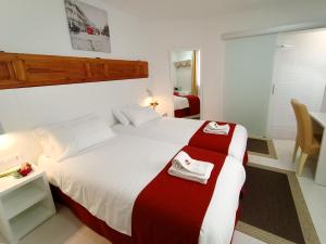 Un dormitorio con una gran cama blanca con sábanas rojas y blancas. en Hostal Royal Cruz, en Madrid