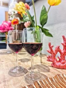dos copas de vino tinto en una mesa con flores en Borro Palace en Cagliari