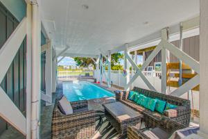 um alpendre com uma piscina e um sofá em 193 High Point em Holden Beach