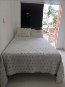 a bed with a white comforter in a bedroom at Casa dos Pinheiros Beira-mar in Mutari