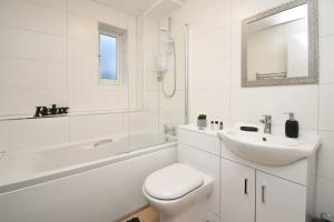 La salle de bains blanche est pourvue de toilettes et d'un lavabo. dans l'établissement Silicon Court -Milton Keynes -4 bedroom Sleeps 7, à Milton Keynes