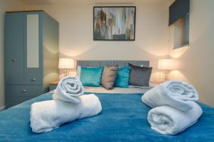 - une chambre avec des serviettes sur un lit bleu dans l'établissement Silicon Court -Milton Keynes -4 bedroom Sleeps 7, à Milton Keynes