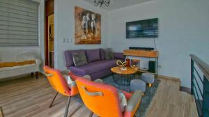 a living room with a purple couch and orange chairs at Nice Apartment in Santiago, Near Popular Places in Santiago de los Caballeros